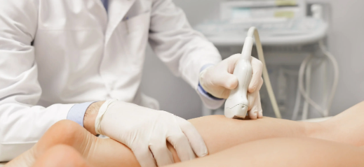 Doctor performing a diagnostic ultrasound on a patient's leg at a vein clinic.